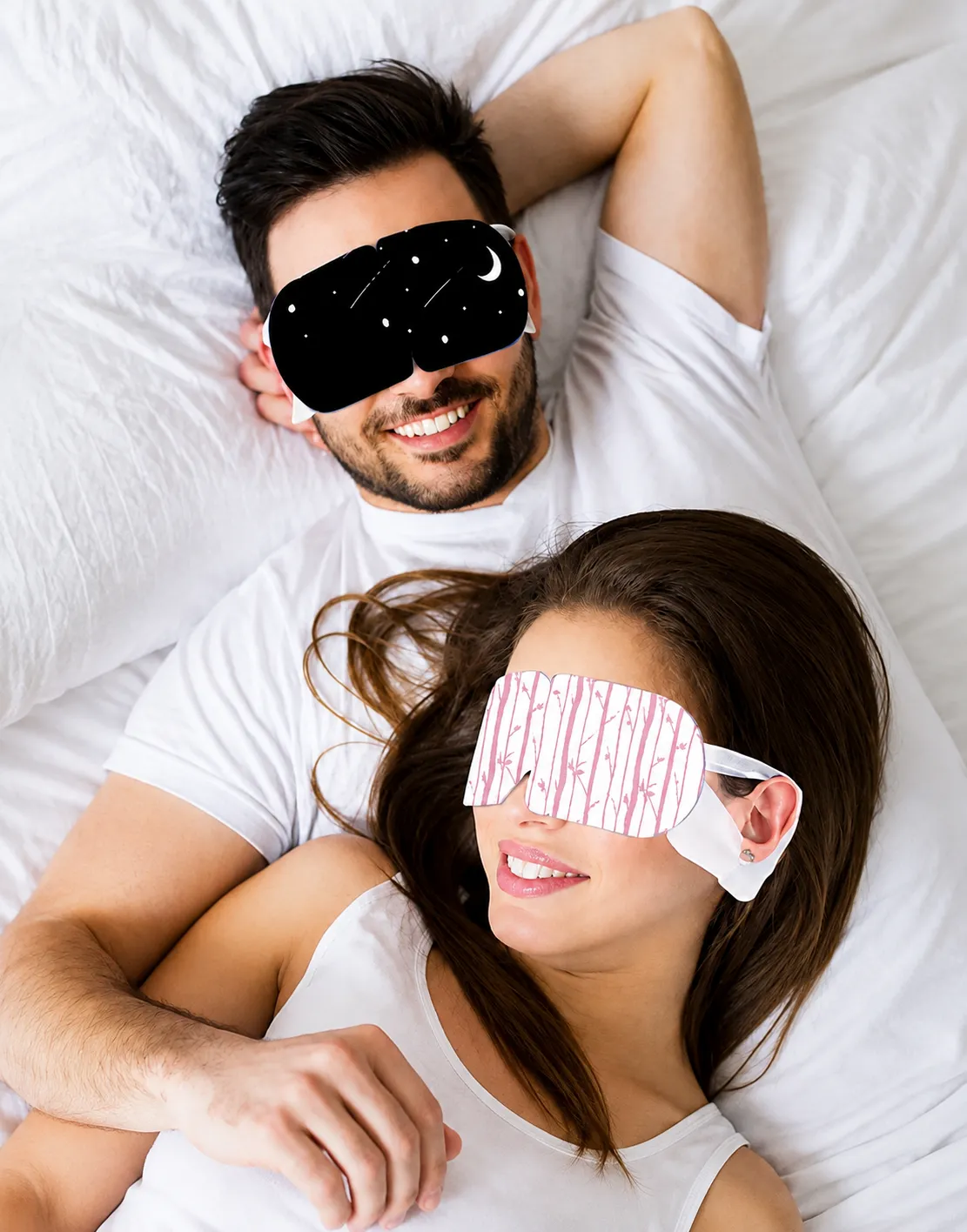 Couple wearing patterned sleep eye masks in bed, relaxing together at bedtime