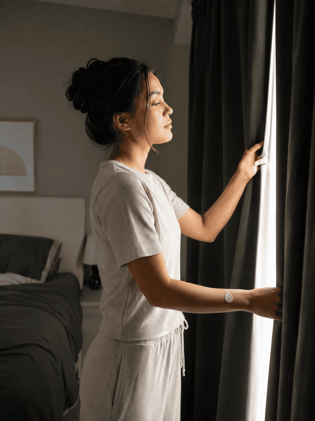Woman closing blackout curtains wearing a sleep patch